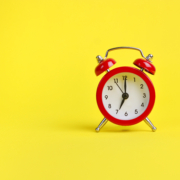 Red alarm clock on a yellow background. Copy space.